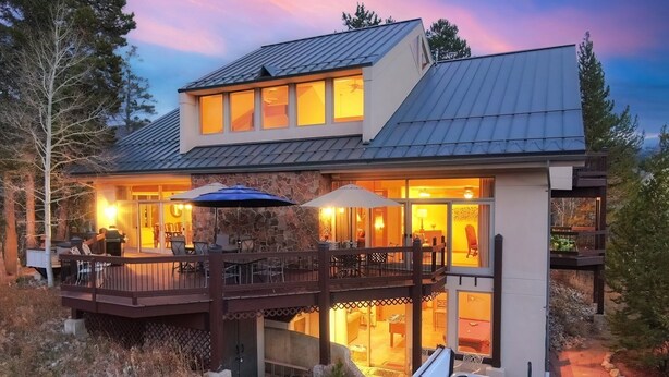 A modern house with a deck, outdoor seating, and a hot tub.