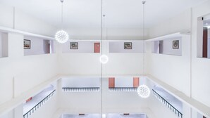 A spacious, multi-level interior with a central open area, railings, and hanging spherical light fixtures. - Mithila Yatri Niwas (Janakpur)
