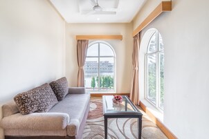 A modern living room with a sofa, a glass coffee table, and large windows offering a view of the cityscape.