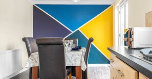 Compact dining area with a geometric design, featuring a dining table, leather chairs, and a kitchenette.