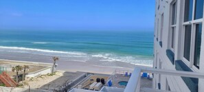 A view of a beach from a balcony with a pool and lounge chairs. - HUGE Beachfront Condo 3 Bed / 2 Bath - 5th Floor! (Daytona Beach Shores)