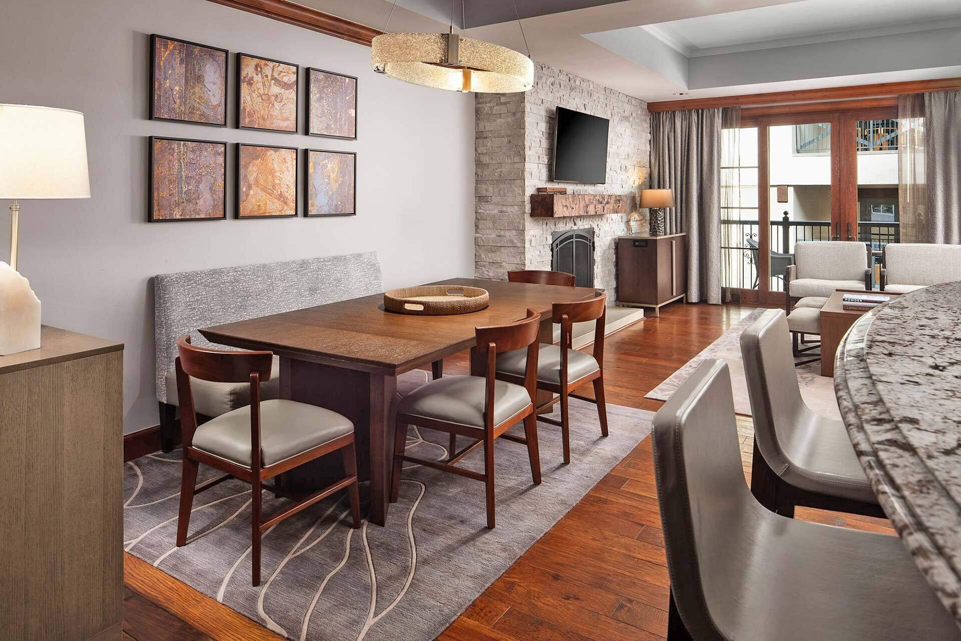 A modern dining area with a wooden table and chairs, a fireplace, and artwork on the wall.