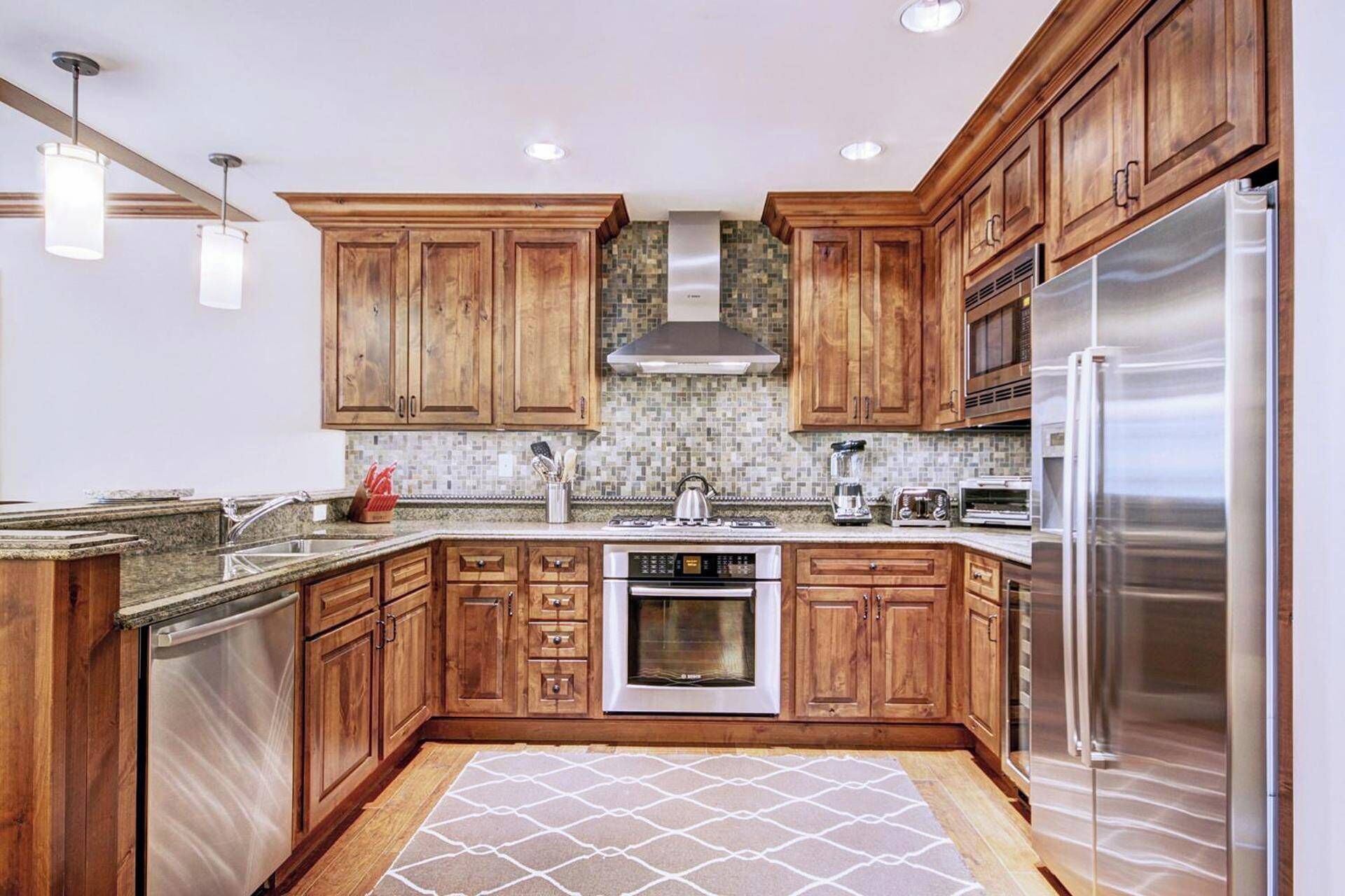 A modern kitchen with wooden cabinets, stainless steel appliances, and a tiled backsplash.