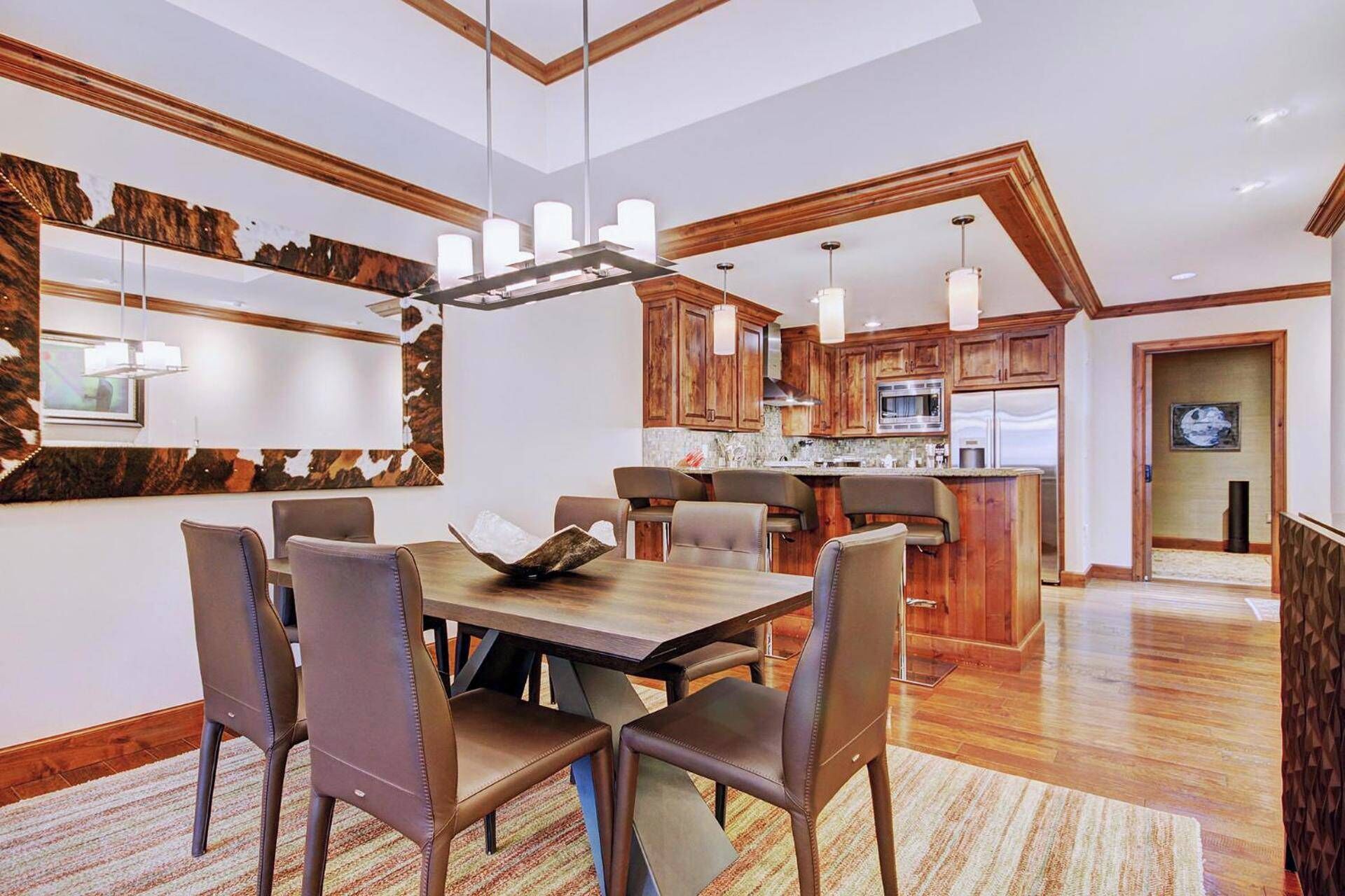 A modern kitchen with wooden cabinets, a central island, and pendant lighting.