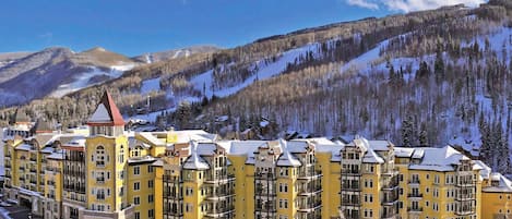 Un hôtel à plusieurs étages, doté d’une façade jaune, qui se dresse sur un fond de paysage montagneux.