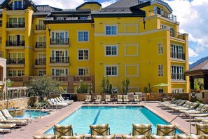 Ein Hotel mit einem großen Pool, umgeben von Liegestühlen und einem Garten.