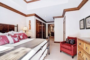 Ein Schlafzimmer mit Bett, Stuhl, Kommode und einem Flur, der zu einem Badezimmer führt.