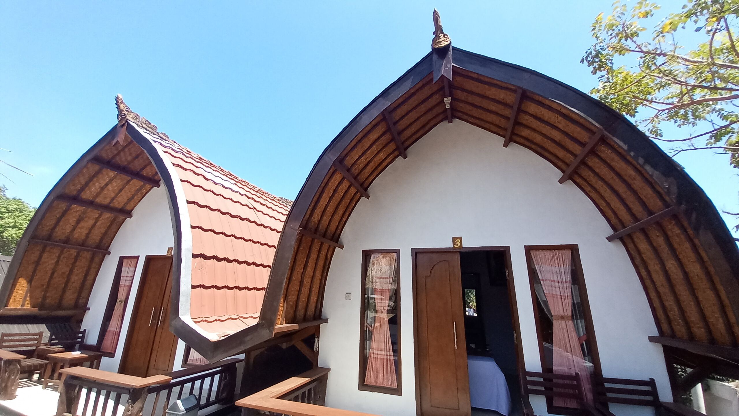 Un edificio tradicional con techo a dos aguas y vigas de madera, que presenta una escalera que lleva a un nivel superior.