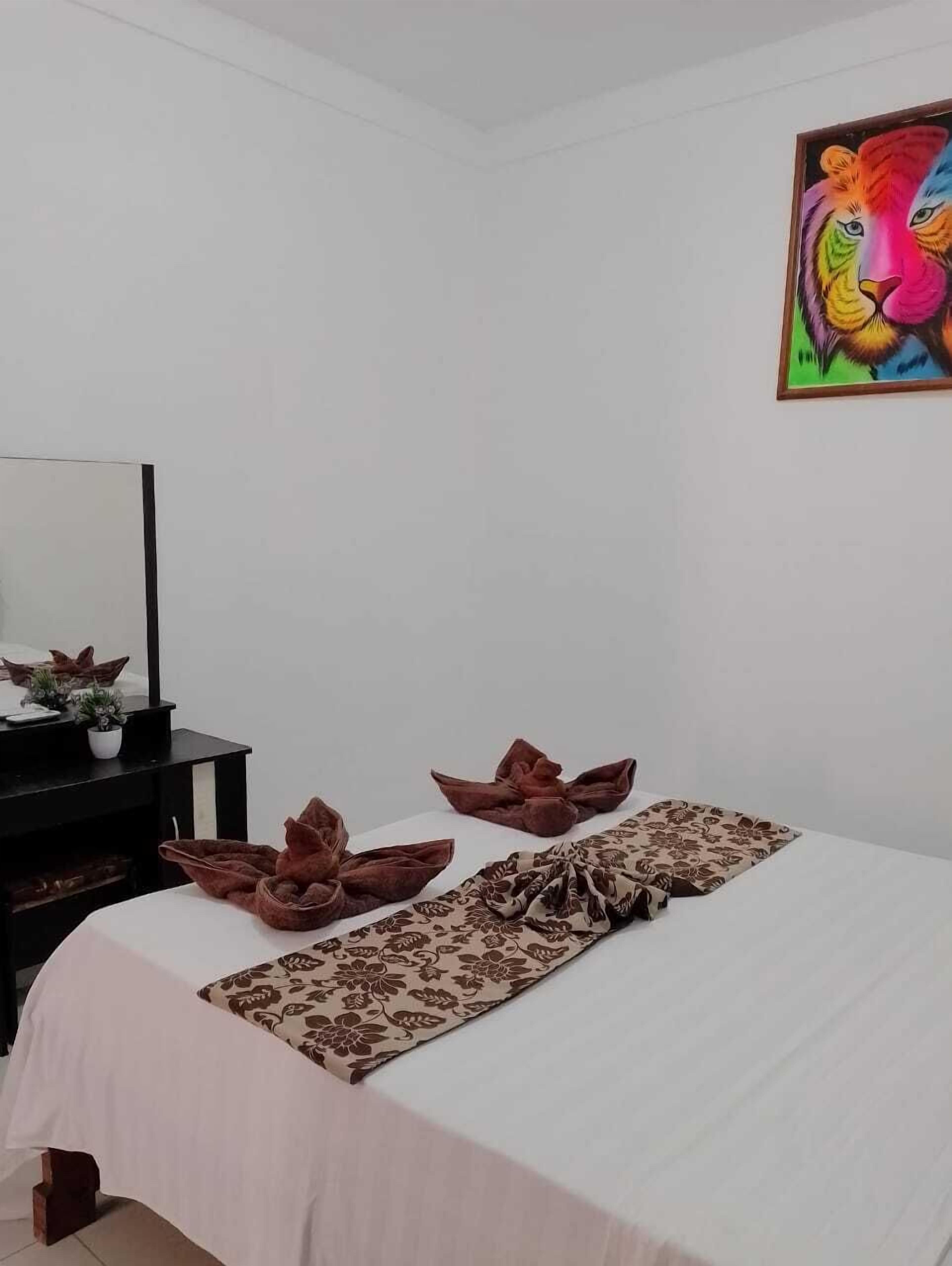 A bedroom with a bed, a desk with a mirror, and a colorful painting on the wall.