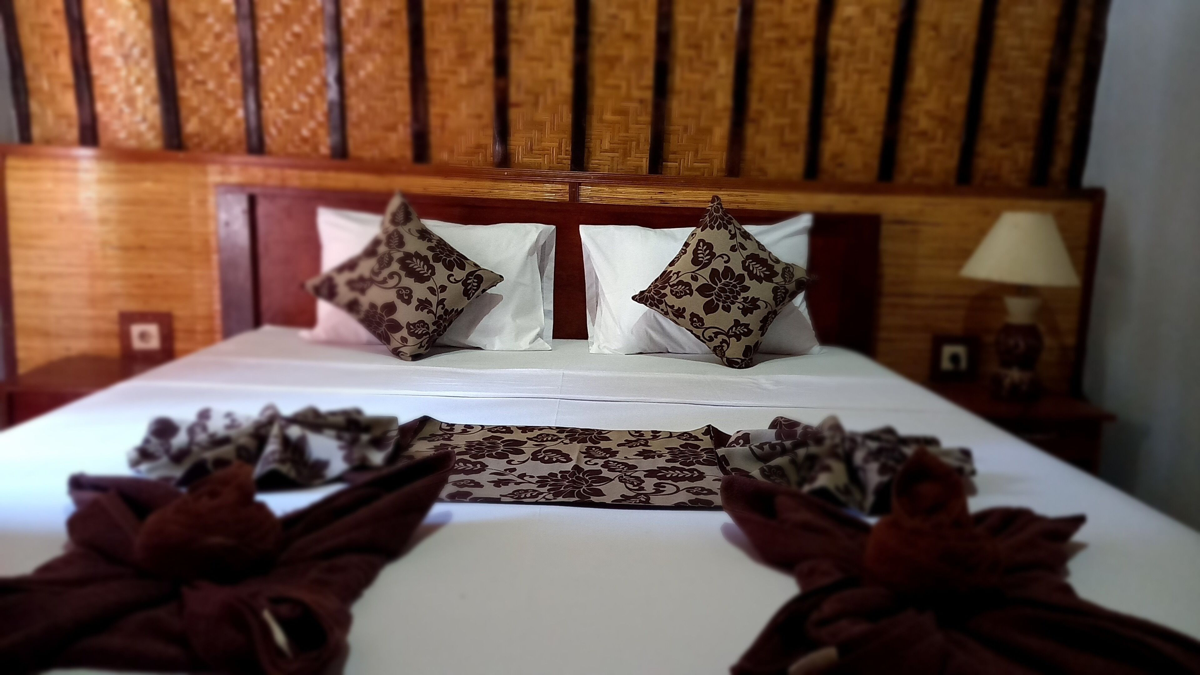 A neatly made bed with floral-patterned pillows and a decorative headboard.