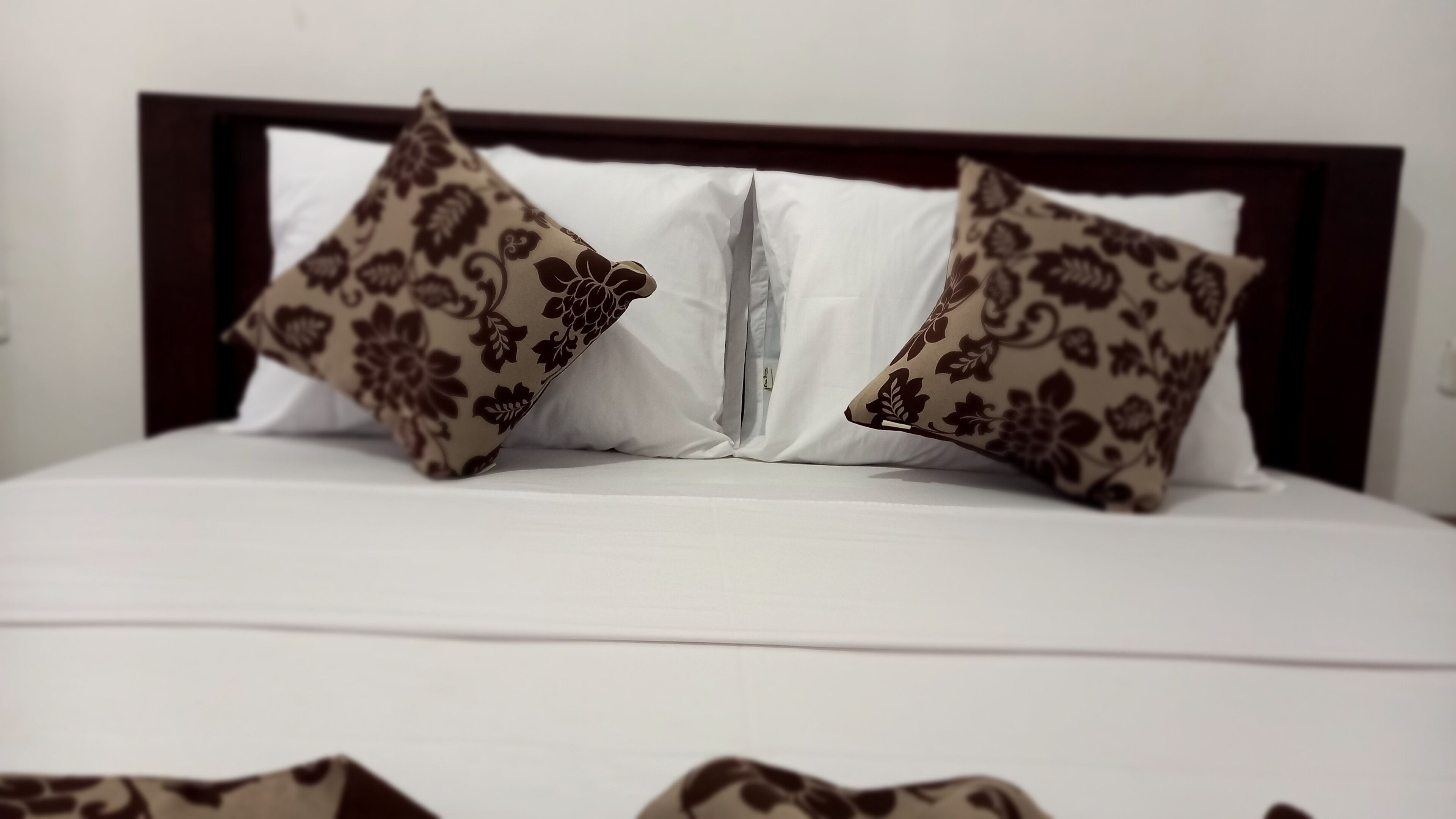 A bed with two decorative pillows and a white mattress.