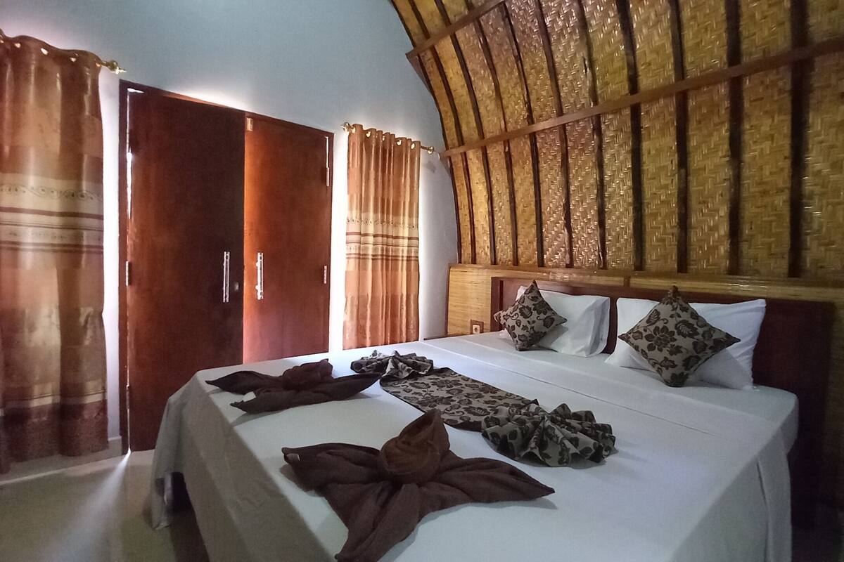 A bedroom with a bed, wooden wardrobe, and curtains.