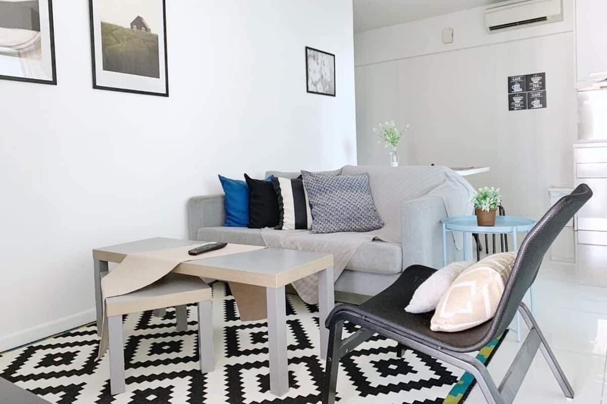 A modern living room with a sofa, a coffee table, a chair, and a small round table with a plant.
