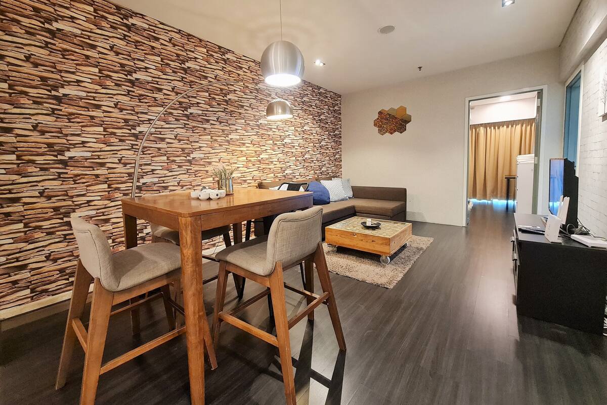 A modern living room with a stone wall, a wooden dining table, and a sofa.
