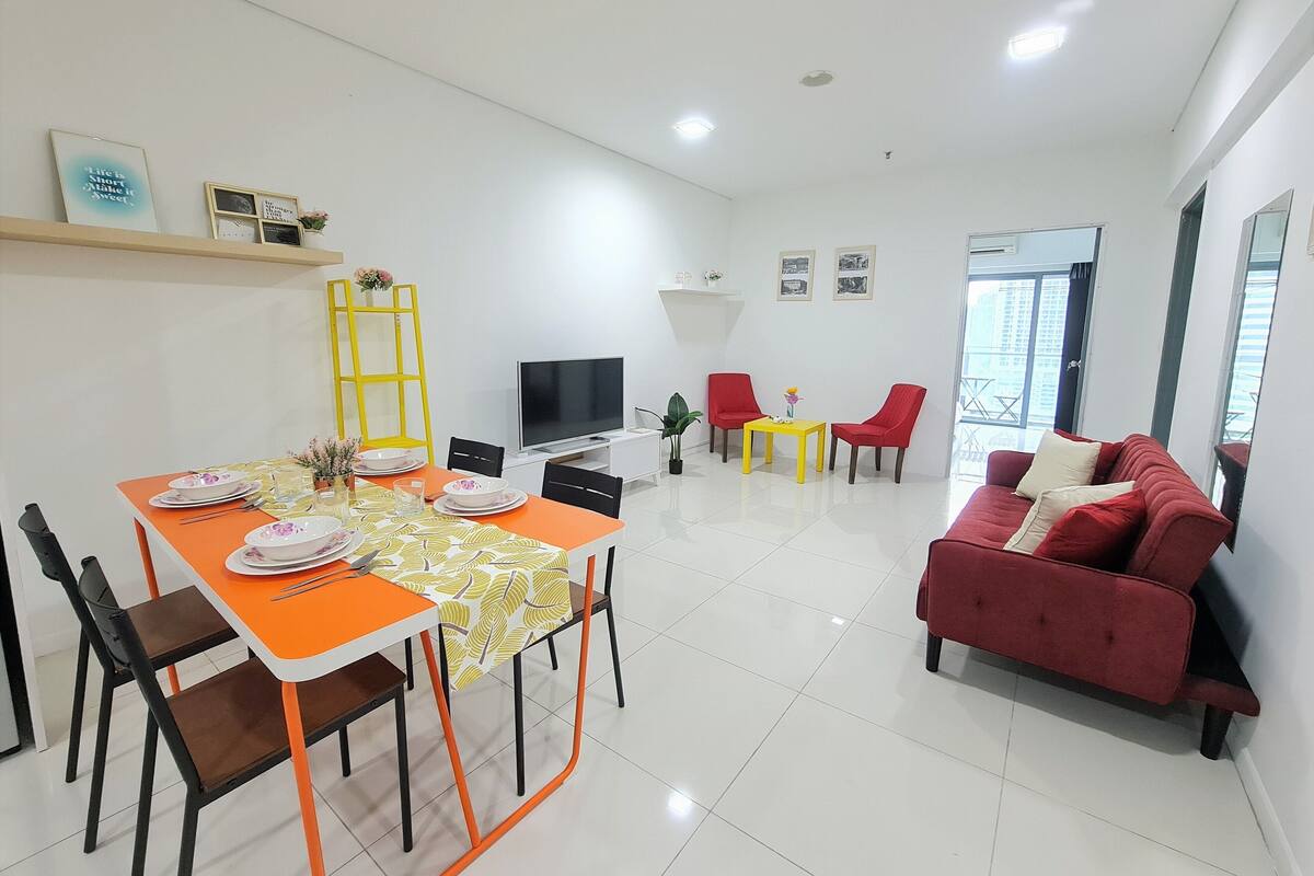 A modern living room with a dining area, a red sofa, and a TV.