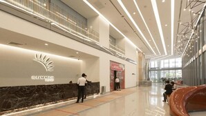 Eine moderne Lobby mit einer Rezeption, einem digitalen Bildschirm und einer gebogenen Sitzgruppe.