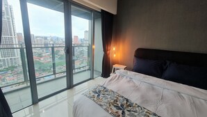 Ein modernes Schlafzimmer mit einem großen Bett, einem Nachttisch und Blick auf eine Stadtlandschaft durch raumhohe Fenster.