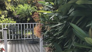 A wooden deck with a white railing, a metal chair, and a small table.