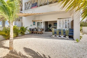 A two-story building with a patio area featuring a table and chairs, potted plants, and a gravel ground. - Belnem Breeze Kas Gosa with a private garden and a rinse tank for your dive gear (Kralendijk)