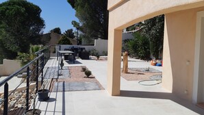 Ein Patio im Freien mit Essgruppe, Topfpflanzen und einem Steinweg.