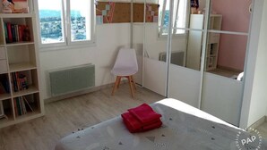 Ein Schlafzimmer mit einem Bett, einem Sessel, einem Bücherregal und einem großen Spiegel.