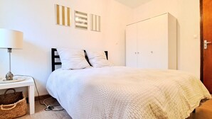 Un dormitorio con cama, mesita de noche, lámpara y armario.