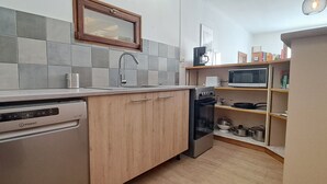 Una cocina compacta con lavavajillas, un lavabo con grifo, microondas y cafetera.