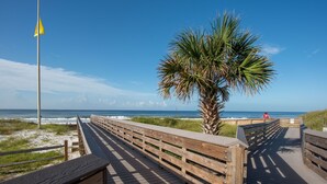A wooden boardwalk leading to the beach with a palm tree and a flagpole. - 30A Endless Summer by AvantStay | 1 Block to Beach | Pool + Tennis (Santa Rosa Beach)