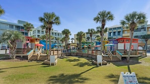 A beachfront area with palm trees, a playground, and colorful buildings. - 30A Endless Summer by AvantStay | 1 Block to Beach | Pool + Tennis (Santa Rosa Beach)