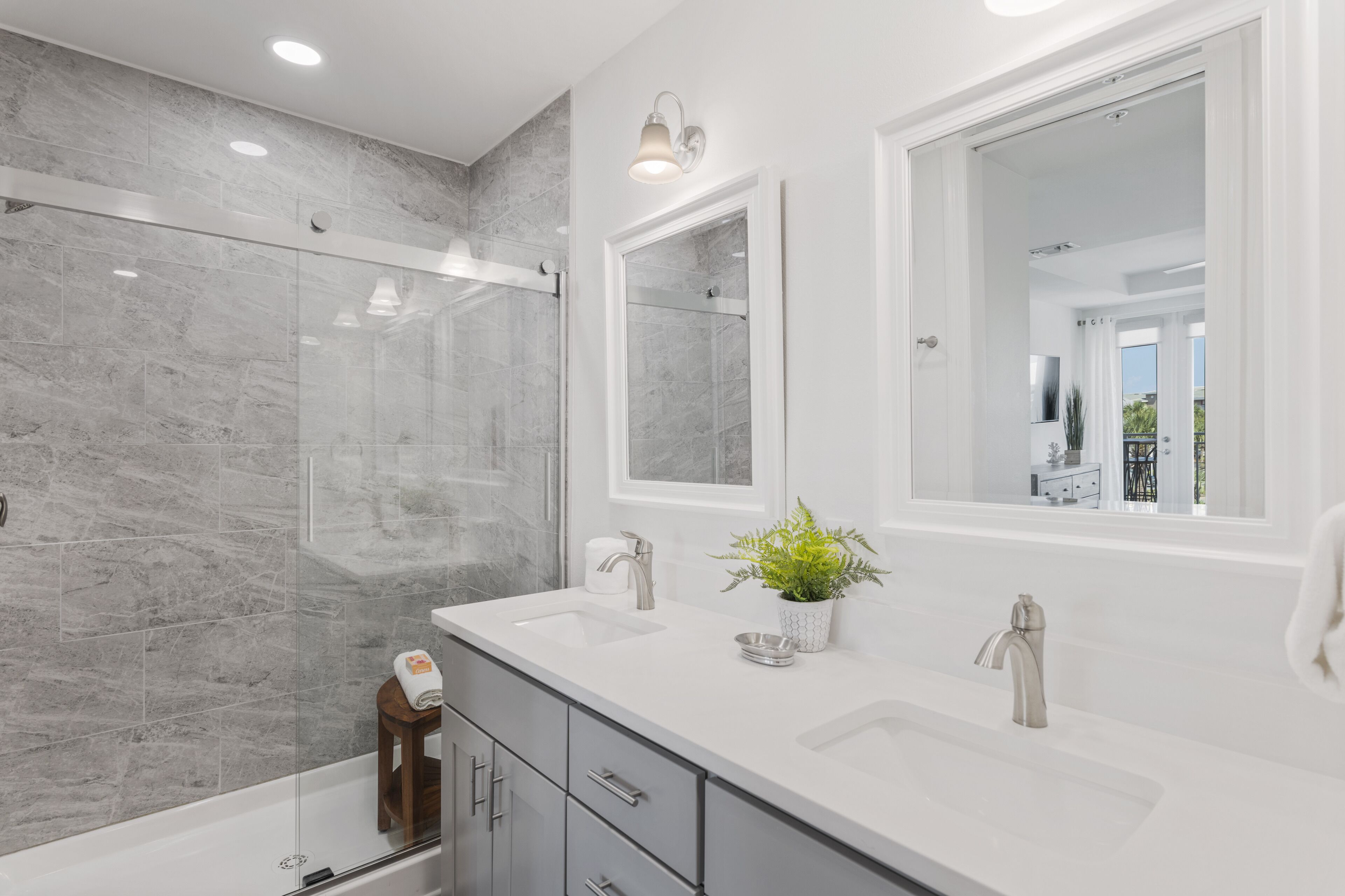 A modern bathroom with two sinks, a glass shower enclosure, and a large mirror.