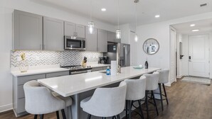 A modern kitchen with grey cabinets, a white countertop, and a central island with bar stools. - 30A Endless Summer by AvantStay | 1 Block to Beach | Pool + Tennis (Santa Rosa Beach)