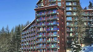 Un hôtel à plusieurs étages doté d’une architecture moderne, caractérisé par une façade en verre remarquable et un revêtement extérieur en briques rouges.