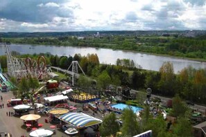 Blick auf einen Park mit einem Fluss, Fahrgeschäften und verschiedenen Gebäuden.