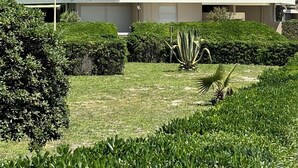 Un immeuble résidentiel à plusieurs étages, doté de balcons, d’un toit plat et d’un jardin bien entretenu.