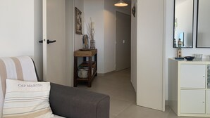 Un salon moderne avec un canapé, une console et un couloir menant à une porte.