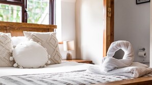 A neatly made bed with a white pillow, a white towel, and a patterned throw. - Church Walk Farm (Snarestone)