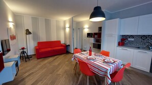 A modern living space with a red sofa, dining table with red chairs, and a kitchen area with white cabinets. - Fantastic farmhouse with swimming pool just a step away from Cinque Terre. (Sesta Godano)