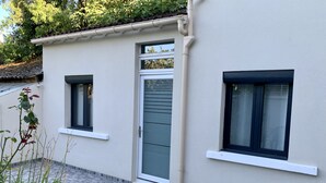 A building with a tiled patio, a door, and two windows.
