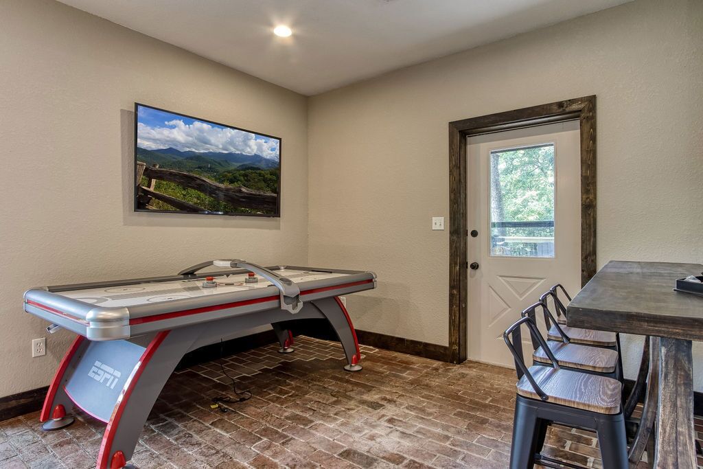 A pool table with a view of mountains, a door, and a table with chairs.