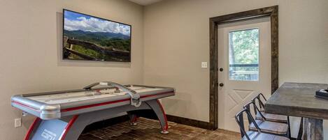 A pool table with a view of mountains, a door, and a table with chairs.