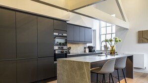 Een moderne keuken met donkere kasten, een groot eiland en barstoelen.