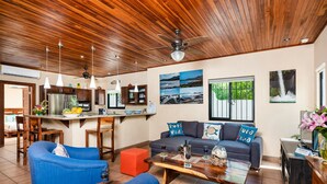 Un salon moderne avec un plafond en bois, un coin cuisine et un espace repas.