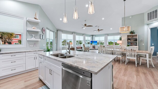 A modern kitchen with white cabinetry, a built-in dishwasher, and a large island with a sink.