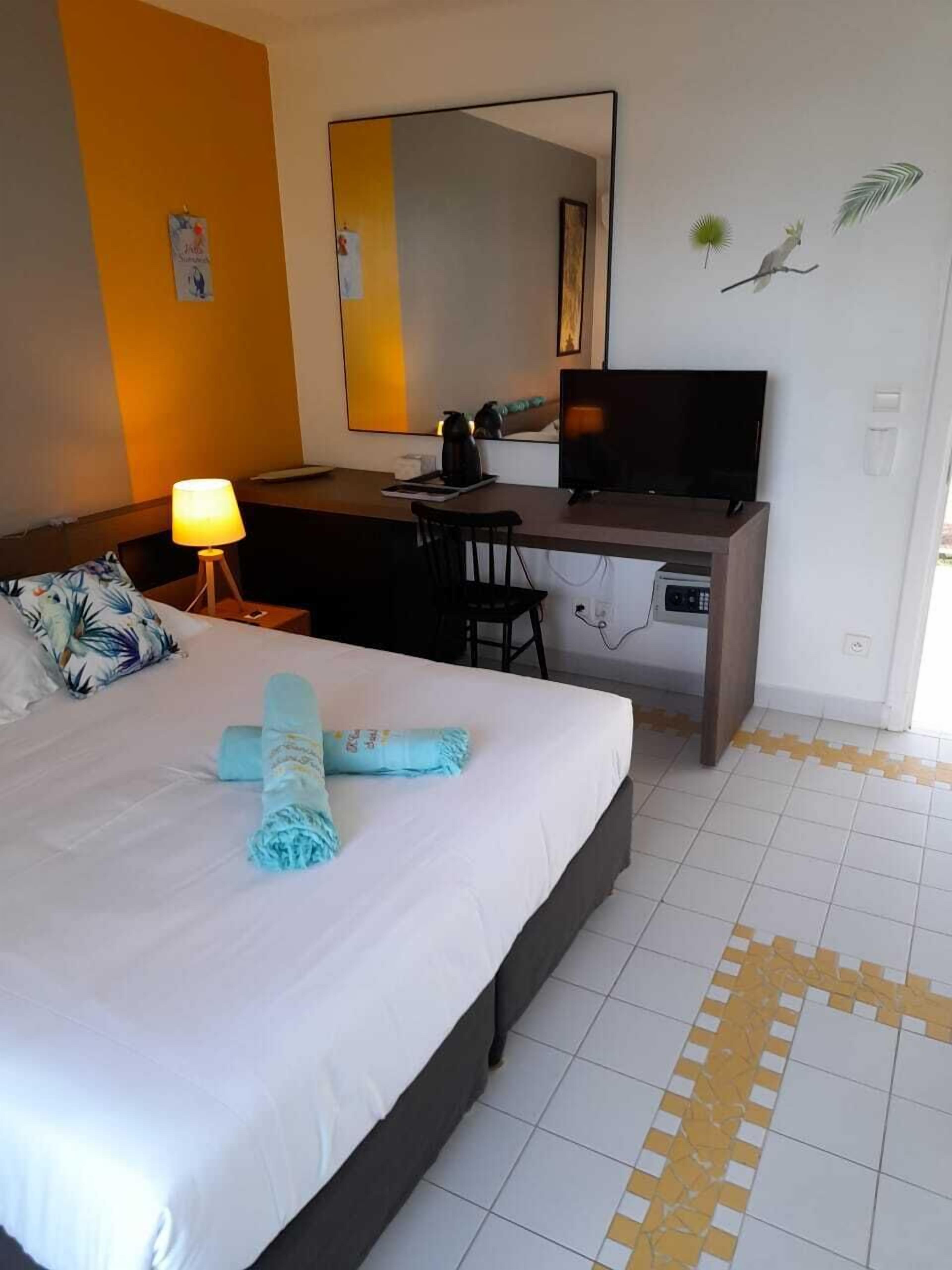 Une chambre d’hôtel équipée d’un lit, d’un bureau, d’une chaise, d’une télévision et d’un miroir.