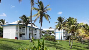 A resort with multiple-story buildings, lush green lawns, and palm trees. - Kaz ananas passion (Saint-François)