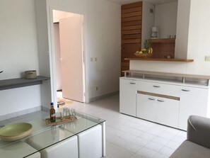 A modern kitchen with white cabinets, a wooden countertop, and a glass coffee table.