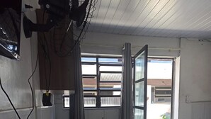 A room with a large window, a door, and a ceiling fan. - Buzios Geriba Aluguel Economico (Búzios)