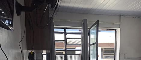 A room with a large window, a door, and a ceiling fan.