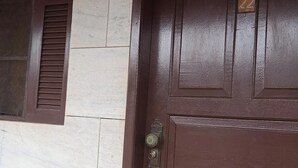 A brown door with a number plate and a window with horizontal slats. - Buzios Geriba Aluguel Economico (Búzios)