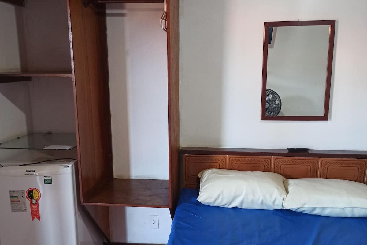 Une chambre avec un lit, une armoire et un petit coin cuisine.